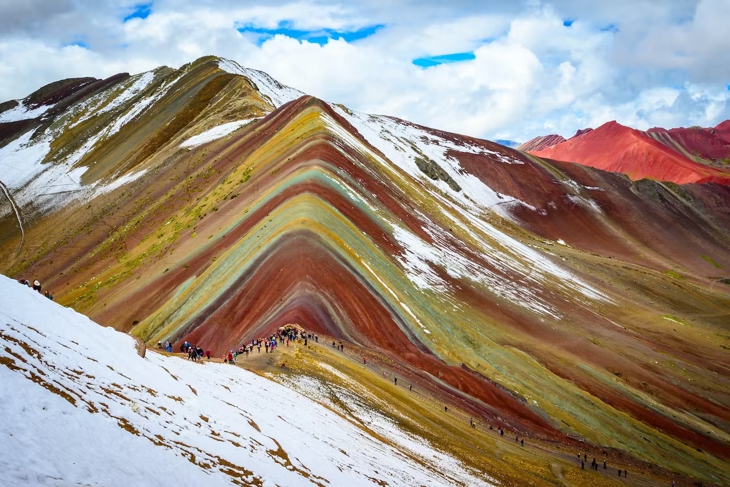 Rainbow Mountain with visitors during the Ausangate Trek 4 days 3 nights, partially covered in snow.